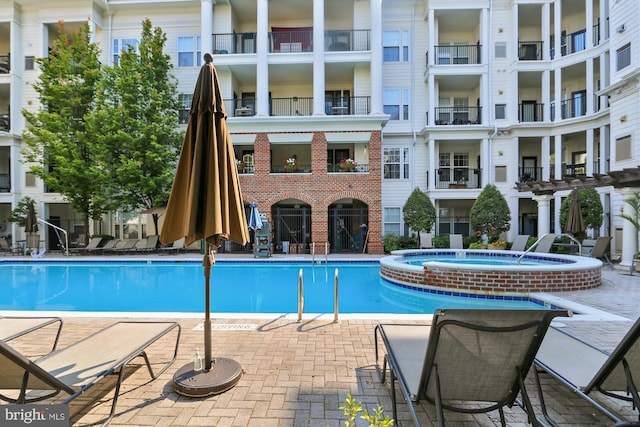 view of pool with a hot tub and a patio area