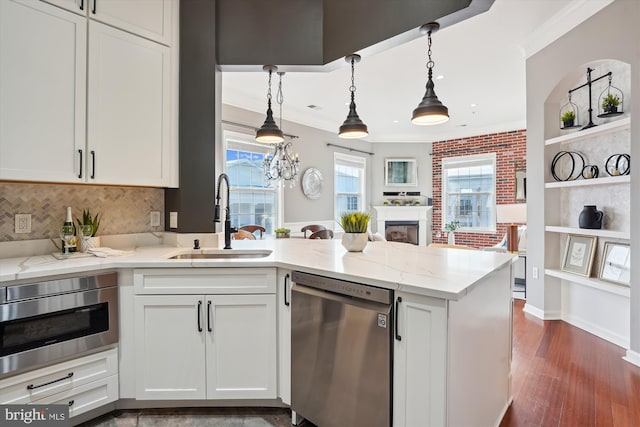 kitchen with sink, white cabinets, ornamental molding, light stone counters, and stainless steel appliances