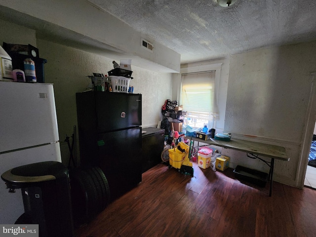 kitchen with black refrigerator, dark hardwood / wood-style flooring, a textured ceiling, and white fridge