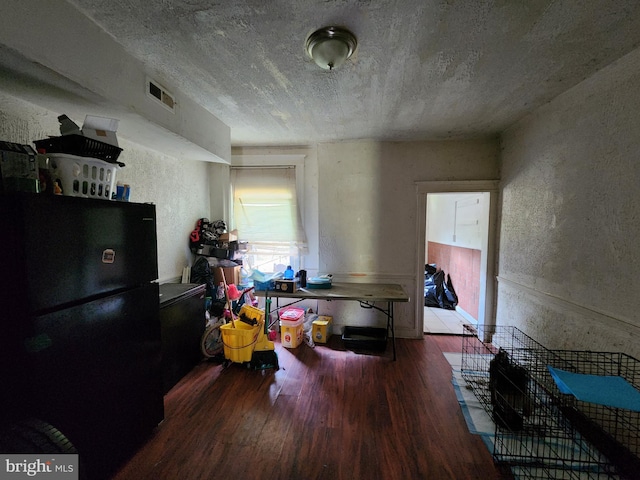 interior space with black fridge and hardwood / wood-style floors