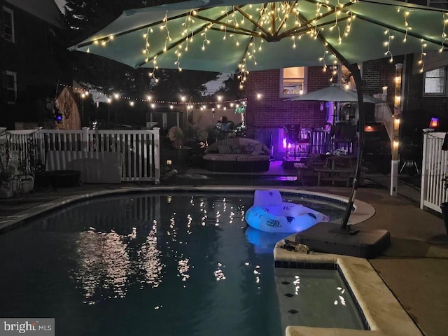 pool at night with a hot tub and a patio