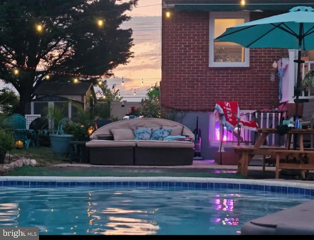 pool at dusk with an outdoor hangout area