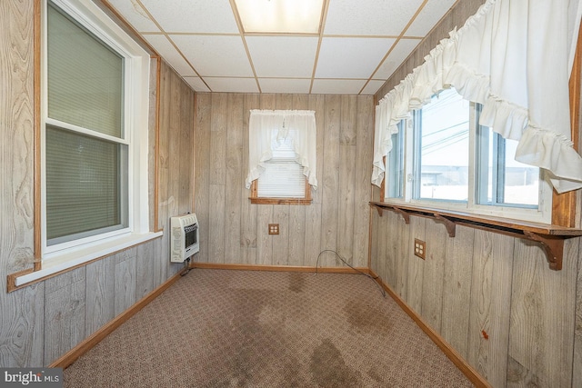 carpeted empty room with a paneled ceiling and heating unit