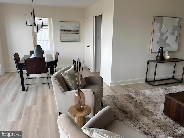 living room with light wood-type flooring and an inviting chandelier