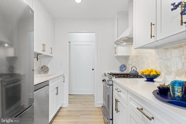 kitchen with white cabinetry, wall chimney range hood, and stainless steel appliances