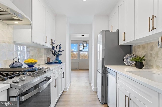 kitchen with tasteful backsplash, wall chimney exhaust hood, stainless steel appliances, and white cabinetry