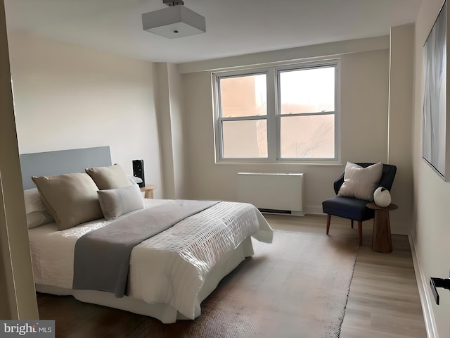 bedroom with radiator and light hardwood / wood-style floors