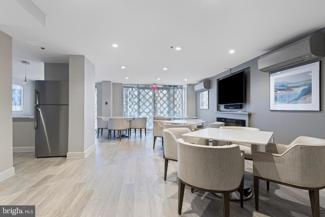 dining space with light wood-type flooring and a wall mounted AC