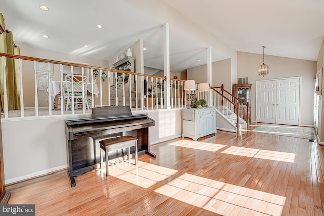 foyer entrance with vaulted ceiling, a notable chandelier, and light wood-type flooring