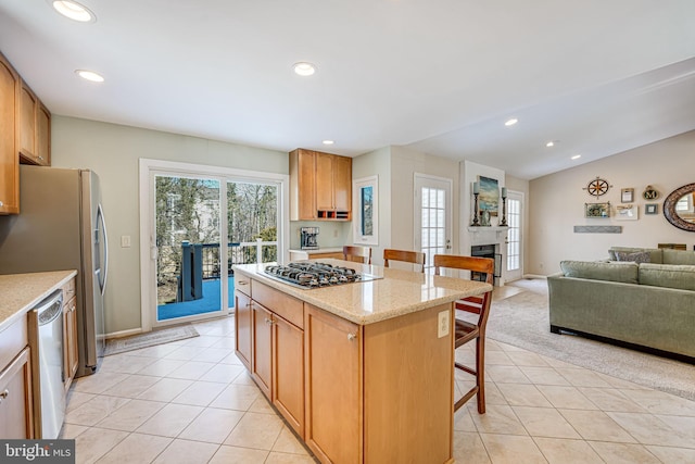 kitchen featuring a breakfast bar, appliances with stainless steel finishes, light tile patterned flooring, and a kitchen island