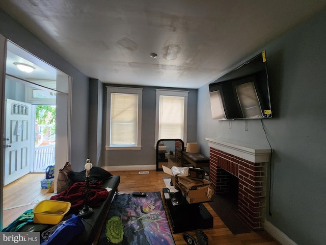 living room with wood-type flooring and a brick fireplace