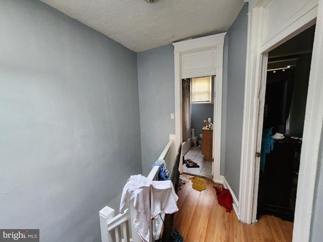 corridor featuring a textured ceiling and light hardwood / wood-style flooring