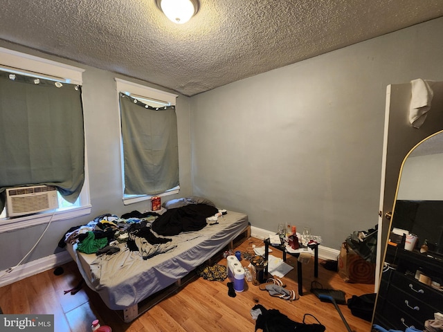 bedroom featuring a textured ceiling, cooling unit, and hardwood / wood-style floors