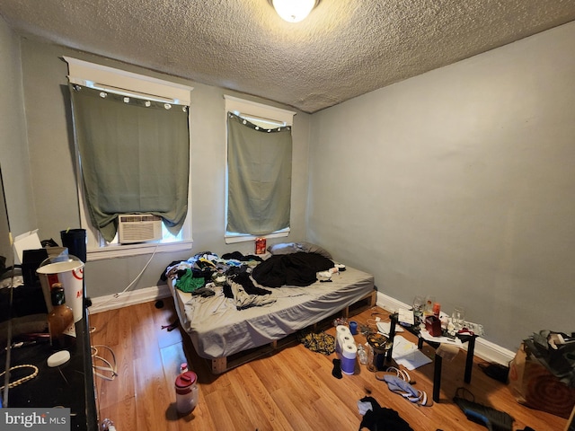 bedroom featuring a textured ceiling, cooling unit, and hardwood / wood-style floors