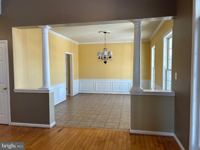 unfurnished dining area with ornate columns, ornamental molding, and light hardwood / wood-style flooring