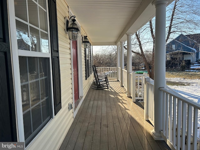 snow covered deck featuring covered porch