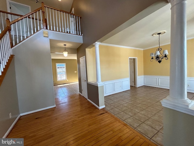 interior space featuring decorative columns, ornamental molding, an inviting chandelier, and light hardwood / wood-style flooring