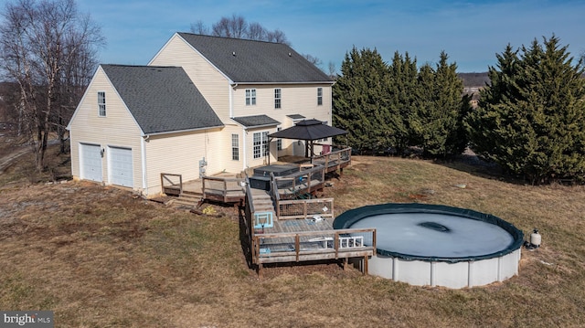 back of house with a garage, a gazebo, a lawn, and a swimming pool side deck