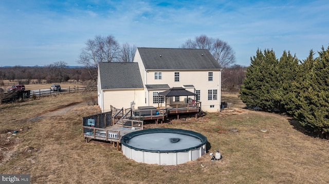 back of property with a gazebo, a pool side deck, and a lawn