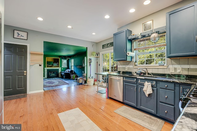 kitchen featuring sink, backsplash, stainless steel dishwasher, and light hardwood / wood-style floors