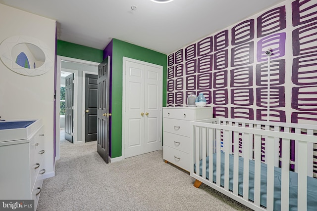 carpeted bedroom featuring a crib and a closet