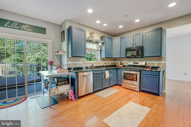 kitchen featuring stainless steel appliances, sink, light hardwood / wood-style floors, and decorative backsplash