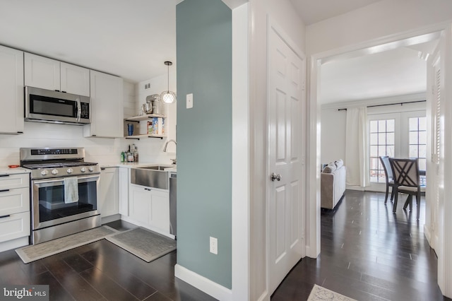 kitchen featuring appliances with stainless steel finishes, dark hardwood / wood-style floors, tasteful backsplash, sink, and white cabinets