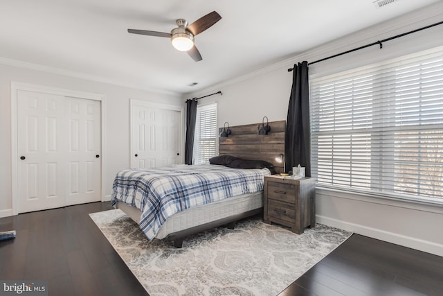 bedroom with multiple closets, ceiling fan, dark hardwood / wood-style flooring, and crown molding