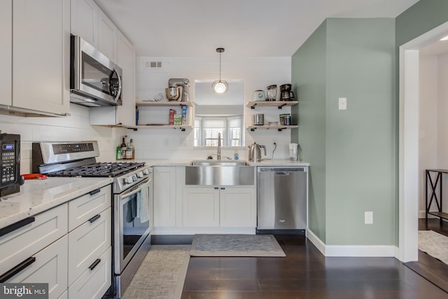 kitchen with sink, pendant lighting, stainless steel appliances, light stone countertops, and white cabinets