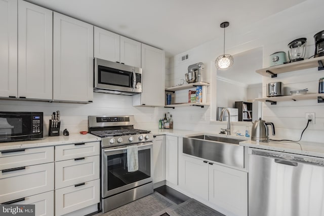 kitchen with sink, decorative light fixtures, stainless steel appliances, light stone countertops, and white cabinets