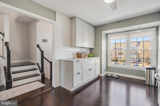 interior space featuring dark wood-type flooring, white cabinets, and ceiling fan