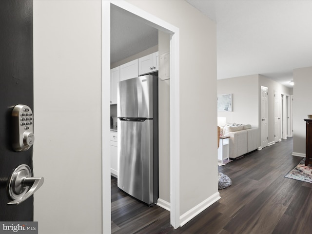 kitchen with baseboards, dark wood-style flooring, freestanding refrigerator, and white cabinetry