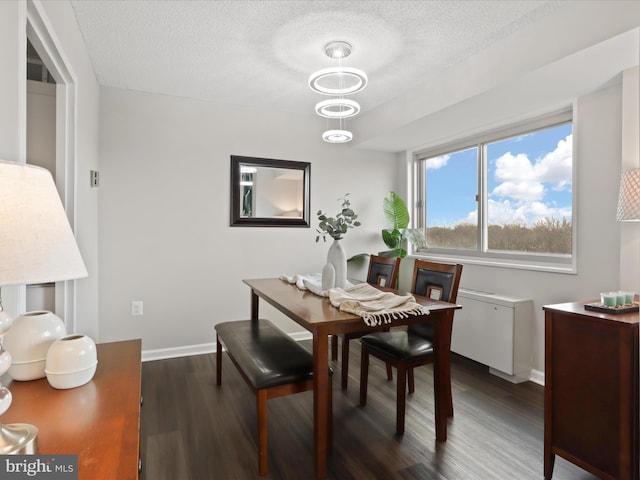 dining space with a textured ceiling, baseboards, and dark wood-type flooring