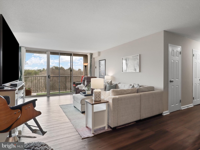 living room with floor to ceiling windows, a textured ceiling, baseboards, and wood finished floors