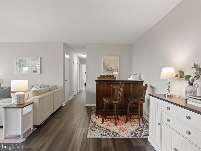 interior space featuring dark wood-style floors, a dry bar, and baseboards