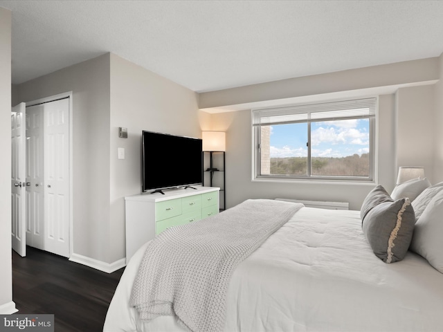 bedroom featuring a closet, dark wood finished floors, and baseboards