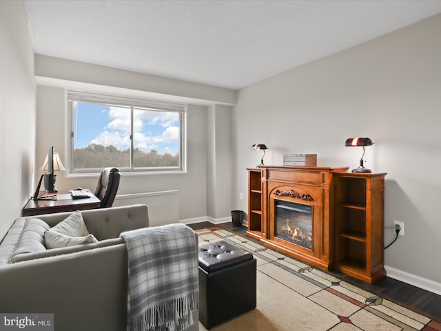 living room with a glass covered fireplace and baseboards