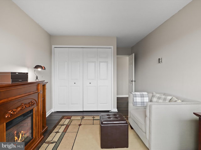 living area featuring a lit fireplace, baseboards, and wood finished floors