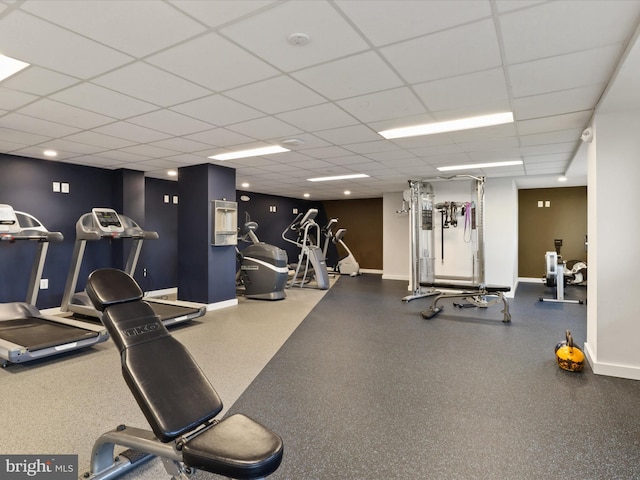 gym with a drop ceiling and baseboards