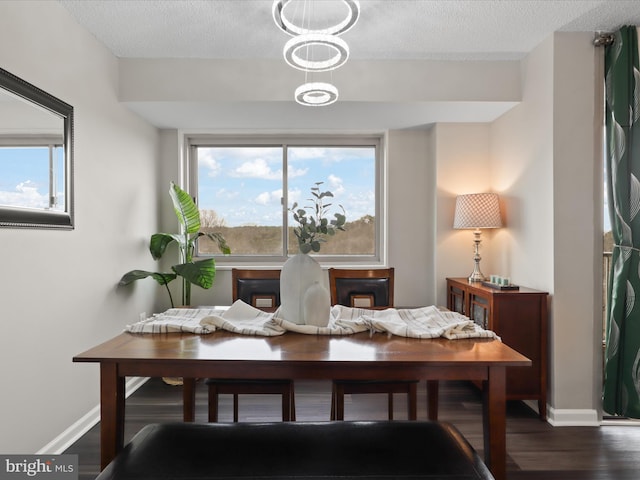 dining space featuring a textured ceiling, baseboards, and wood finished floors