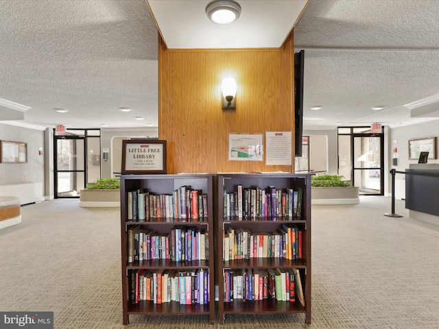 corridor with a textured ceiling, wood walls, carpet flooring, and baseboards