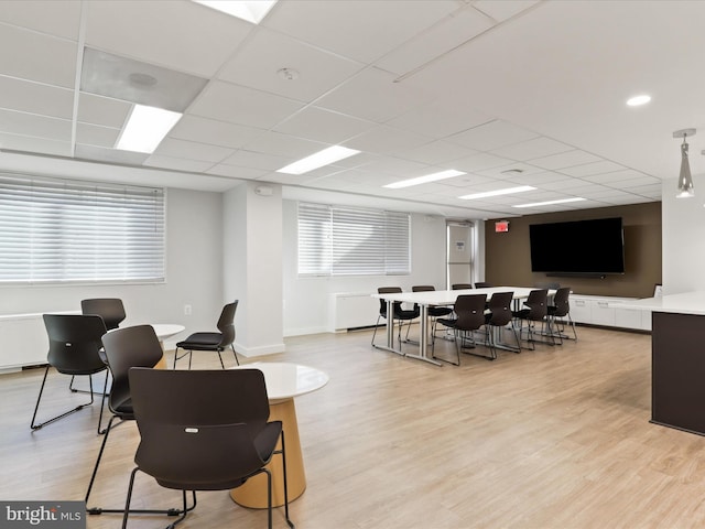 interior space with a paneled ceiling, light wood-style flooring, and baseboards