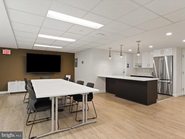 kitchen with light countertops, light wood-style flooring, freestanding refrigerator, white cabinetry, and a peninsula