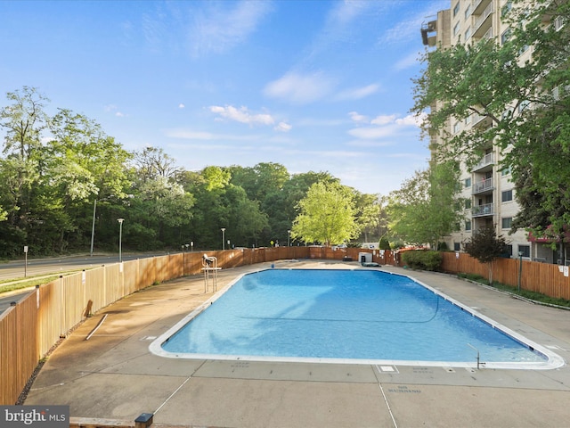 pool with a patio area and fence