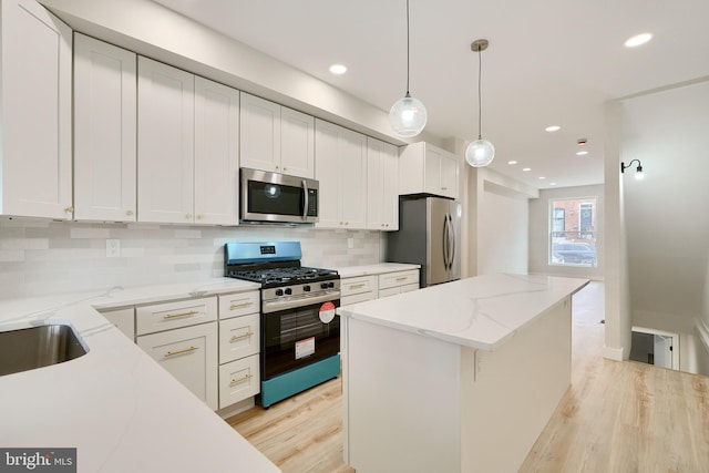 kitchen with pendant lighting, appliances with stainless steel finishes, white cabinetry, and a center island