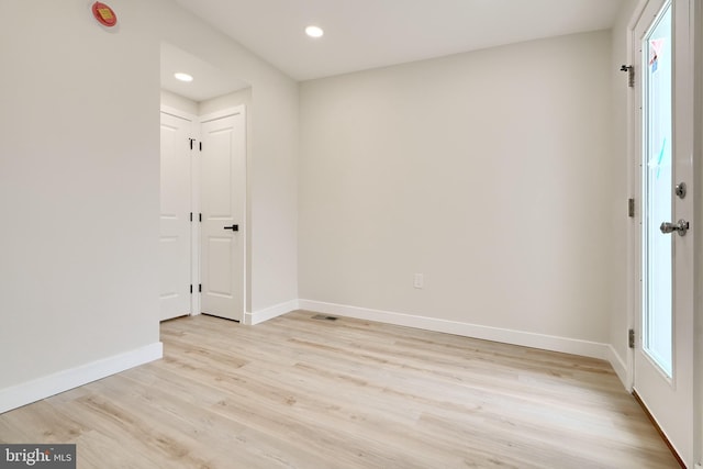 empty room featuring light wood-type flooring, visible vents, baseboards, and recessed lighting