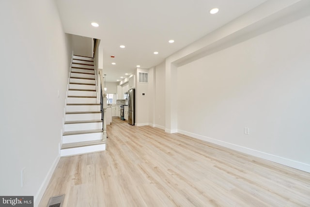 unfurnished living room featuring recessed lighting, visible vents, light wood-style flooring, and stairs