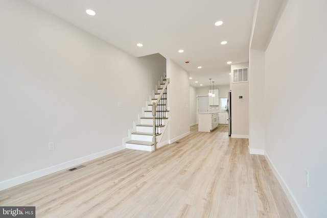 unfurnished living room with light wood finished floors, recessed lighting, visible vents, stairway, and baseboards