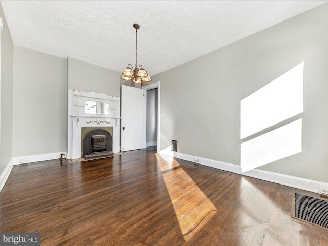 unfurnished living room with dark wood-type flooring, a notable chandelier, and a textured ceiling