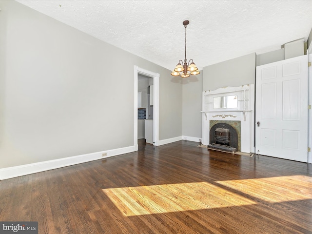 unfurnished living room with dark wood-type flooring, a textured ceiling, and a chandelier